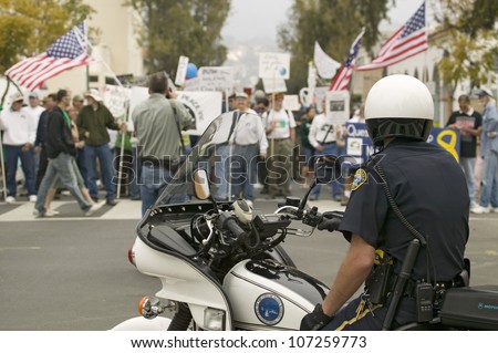 A motorcycle policeman looks at protesters against George W. Bush and the Iraq War at an anti-Iraq War protest march in Santa Barbara, California on March 17, 2007