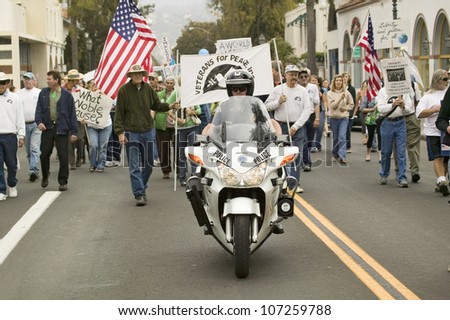 A motorcycle policeman leads parade of protesters against George W. Bush and the Iraq War at an anti-Iraq War protest march in Santa Barbara, California on March 17, 2007