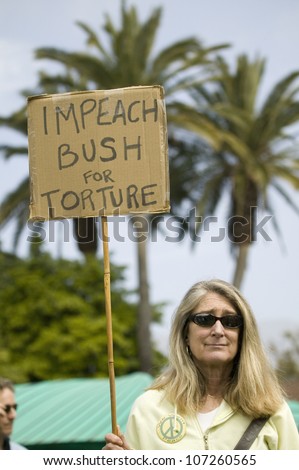 A woman holds a sign saying \