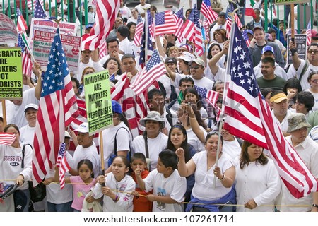 Hispanics wave American flags as immigrants participate in march for Immigrants and Mexicans protesting against Illegal Immigration reform by U.S. Congress, Los Angeles, CA, May 1, 2006