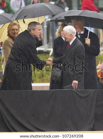 Former US President Jimmy Carter shakes hands with US President George W. Bush during the grand opening ceremony of the William J. Clinton Presidential Center in Little Rock, AK 18 November 2004.