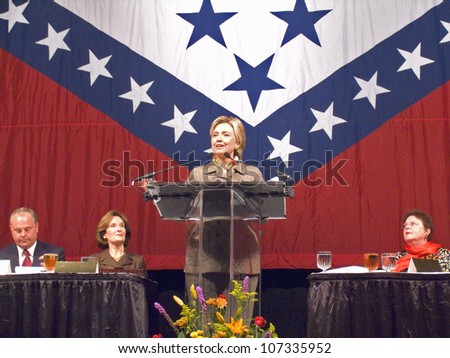 Sen. Hillary Clinton, speaks at a Little Rock, AK luncheon honoring the First Ladies of the state in front of the state flag November 17, 2004 in Little Rock, AK