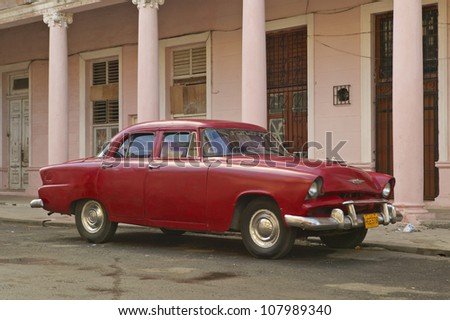 Vintage car in front of pink building in Havana, Cuba