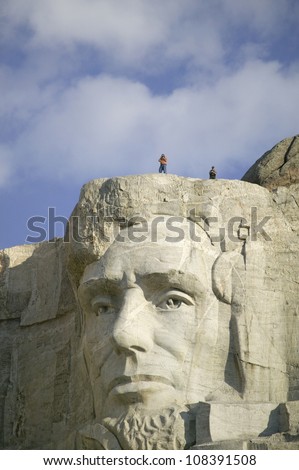 A park ranger and photographer standing above Abraham Lincoln at Mount Rushmore National Memorial, South Dakota