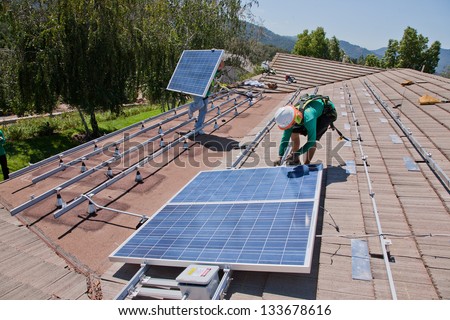 Oak View - October 10: Workers Install Solar Panels On The Roof Of A House On October 10, 2011 In Oak View, Southern California