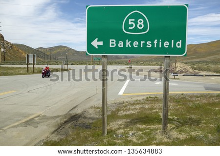 Motorcycle driving past a road sign pointing to Route 58 near Bakersfield CA
