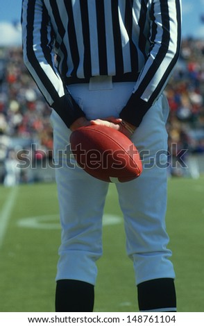 WEST POINT, NEW YORK - CIRCA 1986: Referee holding a football behind his back, West Point, New York