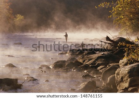 HOUSATONIC RIVER, CONNECTICUT - CIRCA 1980's: Solitary fly fisherman in morning mist, Housatonic River, Connecticut