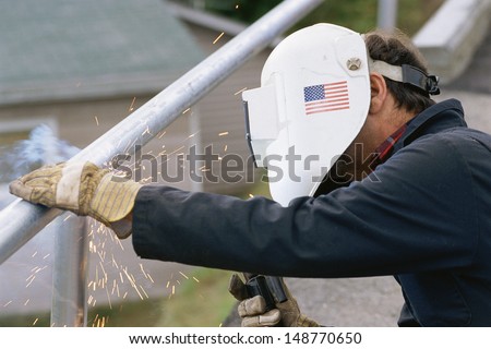 NEW ENGLAND - CIRCA 1980's: Man welding steel railing in New England, USA
