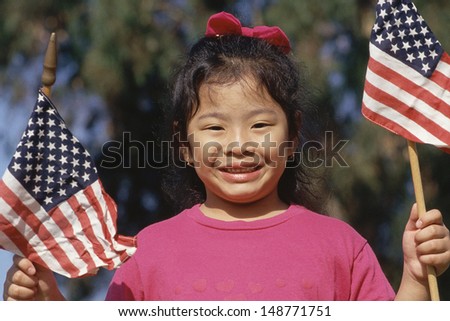 VETERANS CEMETERY, UCLA, LA, CA - CIRCA 1980's: Girl holding American flags