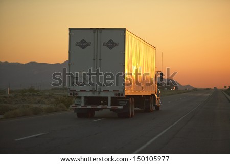 Mojave Desert, Ca - July 29: 18-Wheeler Semi-Trucks At Sunset Hit The Highway Driving Down Interstate Highway 15 Between Los Angeles And Las Vegas Nevada On July 29, 2004 In Southern California