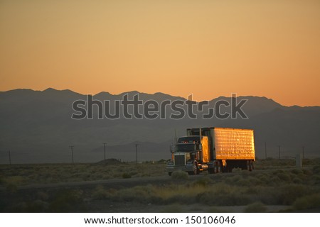 Mojave Desert, Ca - July 29: 18-Wheeler Semi-Trucks Hit The Highway At Sunset Driving Down Interstate Highway 15 Between Los Angeles And Las Vegas Nevada On July 29, 2004 In Southern California