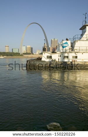 EAST ST. LOUIS, ILLINOIS - CIRCA 2006: Daytime view of tug boat pushing barge down Mississippi  River in front of Gateway Arch and skyline of St. Louis, USA