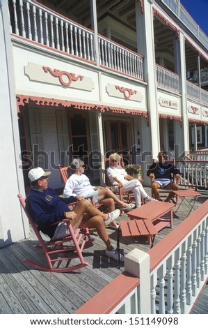 CAPE MAY, NEW JERSEY - CIRCA 1980\'s: Tourists relaxing on a porch of a Victorian home, Cape May, NJ