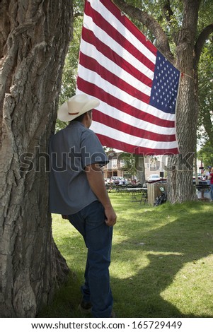 Cowboy looks at American flag in Town Park, Ridgway Colorado