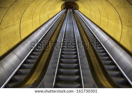 An empty escalator moves through oval tube of light to the Washington D.C. Metrorail commuter trains