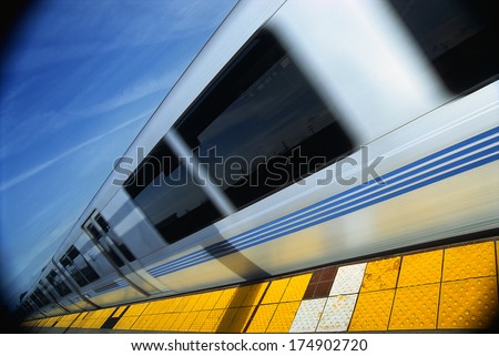 This is the Bart Metro Rail. It is the Bay area rapid transit system. The train is shown at an angle with the end of the train getting smaller into infinity next to a tile floor platform.