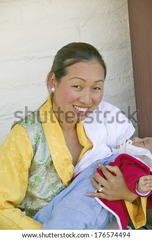 Tibetan woman in traditional dress holds child during Amitabha Empowerment Buddhist Ceremony, Meditation Mount in Ojai, CA