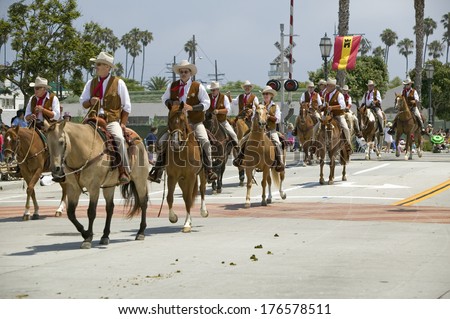 Cowboys riding down street on horseback during opening day parade down State Street, Santa Barbara, CA, Old Spanish Days Fiesta, August 3-7, 2005