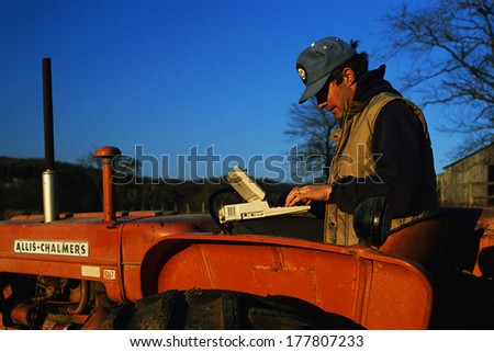 This is a close up of a farmer using a computer on his tractor.
