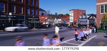 This is main street depicting small town America.  There are school children and a teacher crossing in the crosswalk.