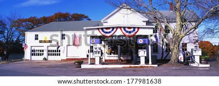 This is Hanna's General Store which is also a gas station. It is a white building, flying red, white and blue banners from its facade. It is a typical small town store.