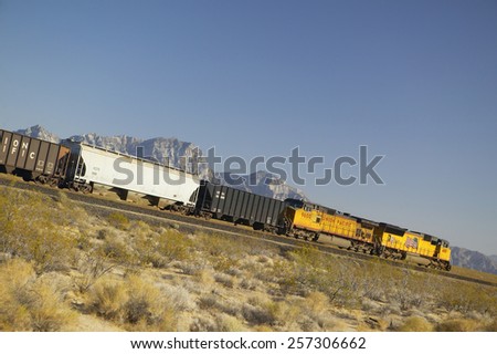 Freight train travels through desert and mountainous areas of Mojave Desert in Southern California