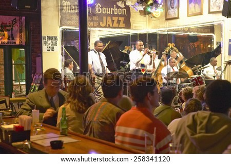 Maison Bourbon Jazz Club with Dixieland band and trumpet player performing at night behind bar with drinking customers in French Quarter in New Orleans, Louisiana