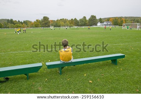 A boy rests on a bench during school soccer practice, New Hampshire