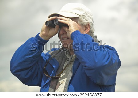 Bird watcher with binoculars in spring grasslands and mountains, Centennial Valley, near Lakeview, MT