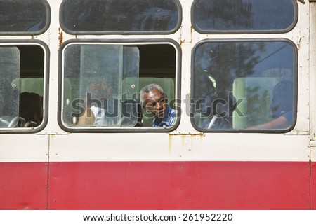 Cuban man looking through window of moving bus in Havana, Cuba