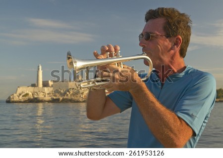 A trumpet player playing music in front of Castillo del Morro, El Morro Fort, across the Havana channel, Cuba