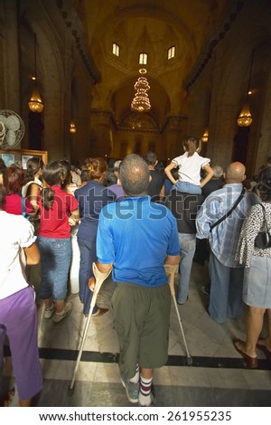 Man on crutches observing Catholic Sunday service in Catedral de la Habana, Plaza del Catedral, Old Havana, Cuba
