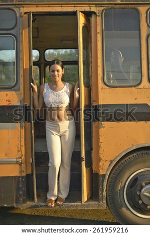 Smiling girl posing in front of an old school bus in the Valle de Vinales, in central Cuba