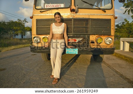 Smiling girl posing in front of an old school bus in the Valle de Vinales, in central Cuba