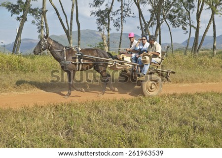 Horse drawn cart and three people traveling through countryside of central Cuba