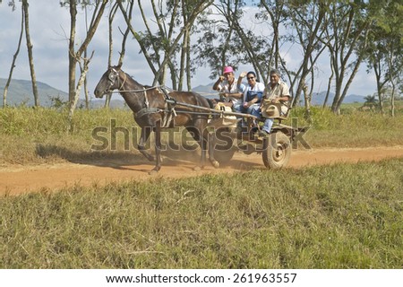 Horse drawn cart and three people traveling through countryside of central Cuba