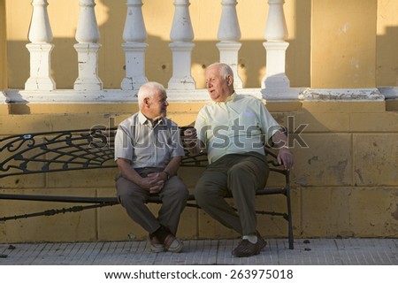 Two older men talk on bench of village of Southern Spain off highway A49 west of Sevilla