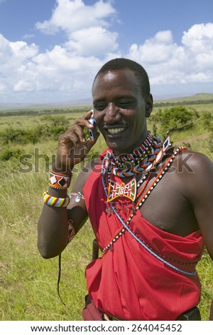 Masai in red toga talks on his cell phone from the grasslands of the Lewa Wildlife Conservancy in North Kenya, Africa