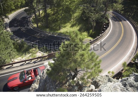 Red convertible driving on Iron Mountain Road, Black Hills, near Mount Rushmore National Memorial, South Dakota