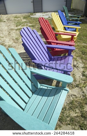 Rainbow colored wooden chairs, known as Maine Chairs, standing in a row outside on the Eastern Shore, Maryland