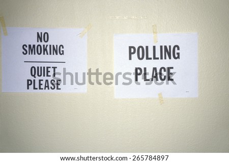 Signs taped to the wall in a polling place read No Smoking and Polling Place