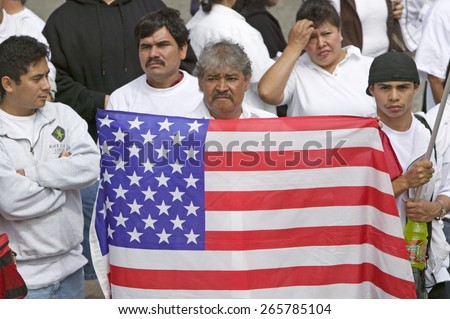 Latin American man holds US flag with hundreds of thousands of immigrants participating in march for Immigrants and Mexicans protesting against Illegal Immigration, Los Angeles, CA, May 1, 2006