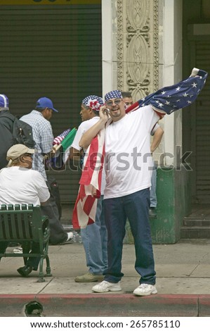 Hispanic man on cellphone with American flag participates in march for Immigrants and Mexicans protesting against Illegal Immigration reform by U.S. Congress, Los Angeles, CA, May 1, 2006