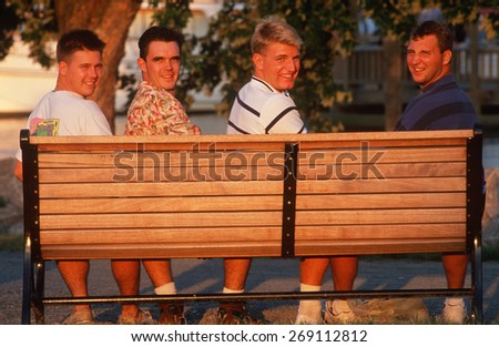 Four college aged men on a park bench in Alexandria, VA