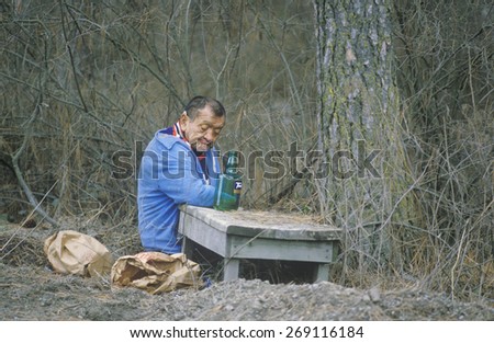 A homeless man sitting on the ground with a bottle of alcohol, Bonners Ferry, ID