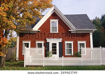 Red wooden house with white picket fence in autumn, New England