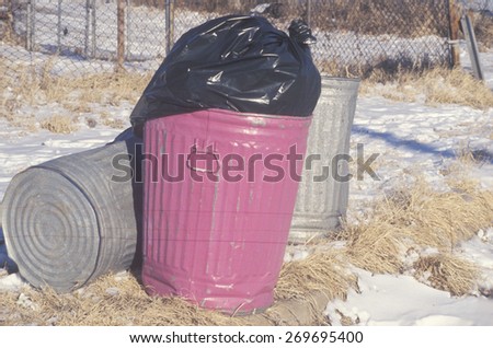 A full pink trash can waiting for pickup
