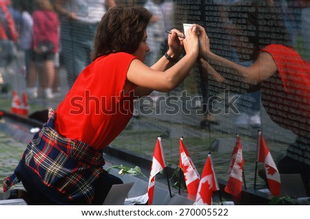 Woman tracing a name of a soldier at Vietnam Memorial Wall, Washington D.C.