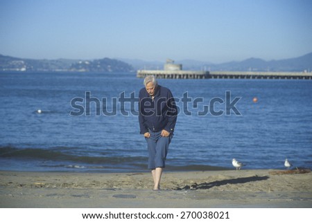 Barefoot man walking at beach, San Francisco, California